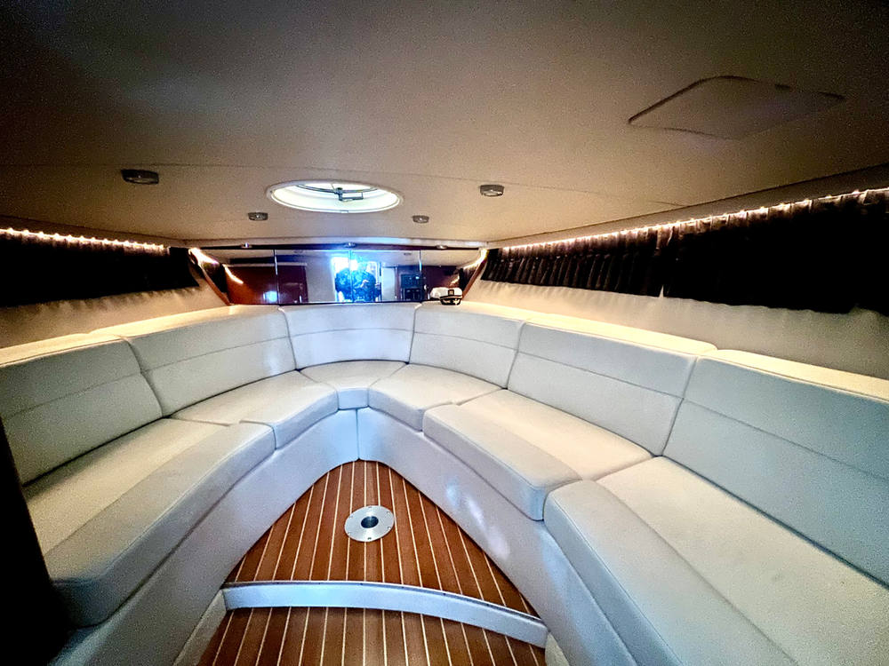 Cabin lounge below deck with wraparound seating and teak sole