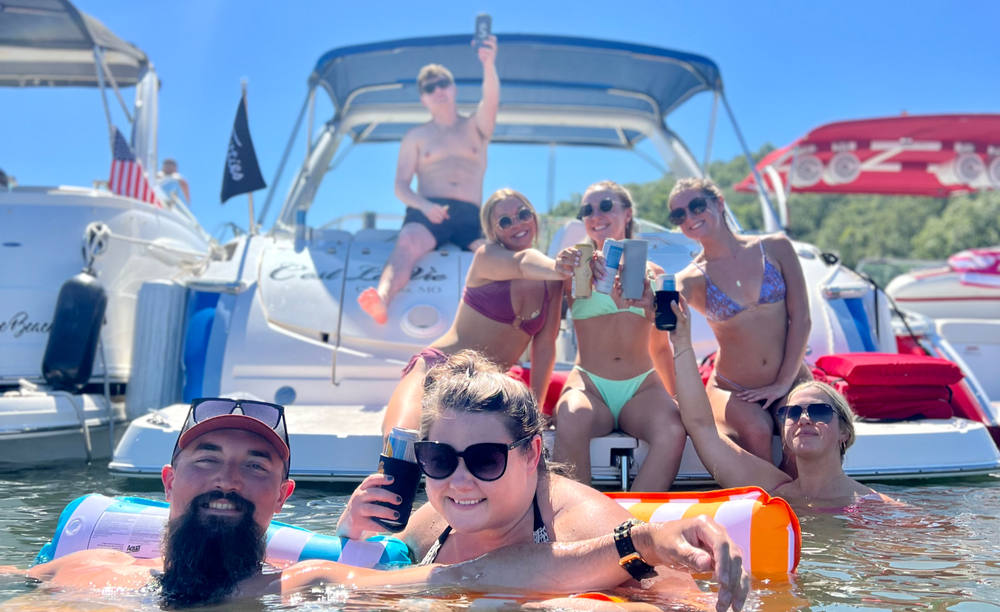 Guests floating in Party Cove beside the boat with drinks in hand